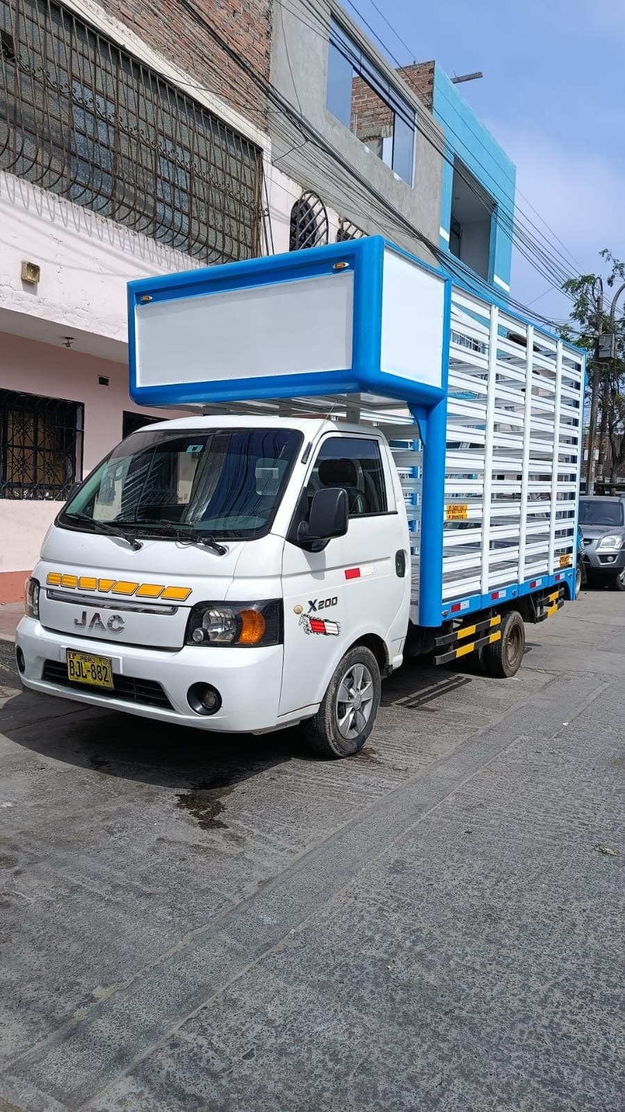 Camioncito blanco JAC con estructura azul para flete terrestre